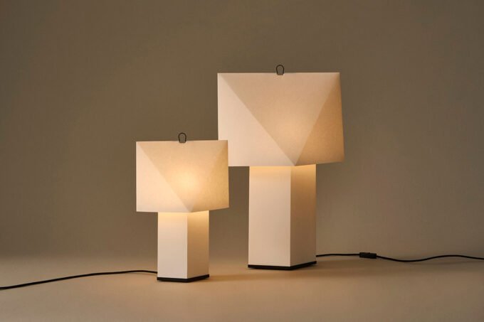 Aplat Table Lamp by CPRV for HAY, a folded paper lamp with a minimalist design, sitting on a table.