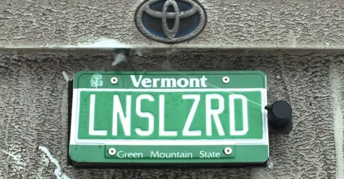 Crystal Clear Views: The Ingenious Backup Camera Cleaner Hiding in Plain Sight 7 The Lens Lizard module discreetly installed behind a car's rear license plate, showing its nozzle and self-contained design.