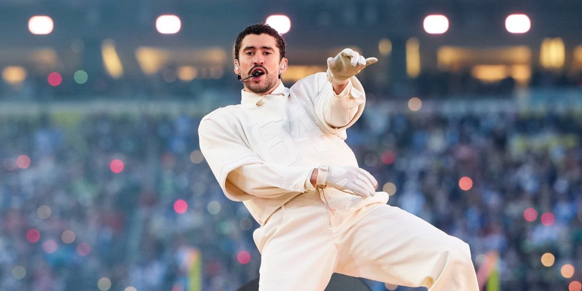 Bad Bunny performing on stage during a Super Bowl halftime show, viewed from the stadium stands.
