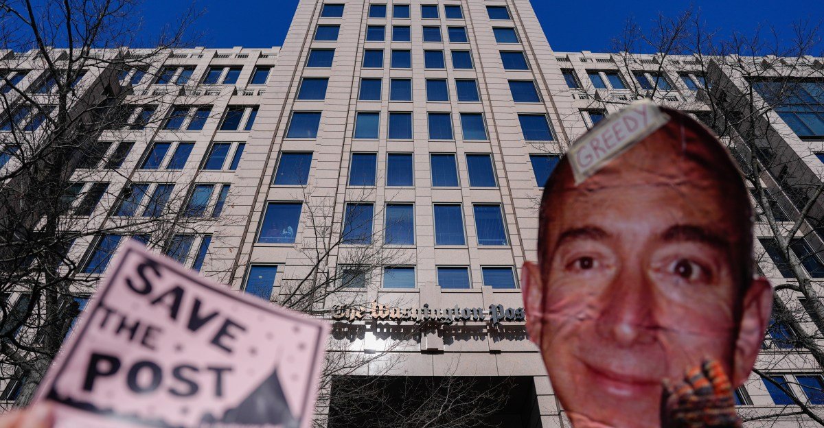 Demonstrators hold a "Save The Post" sign next to a cutout image of Jeff Bezos during a rally outside The Washington Post headquarters in Washington, DC.