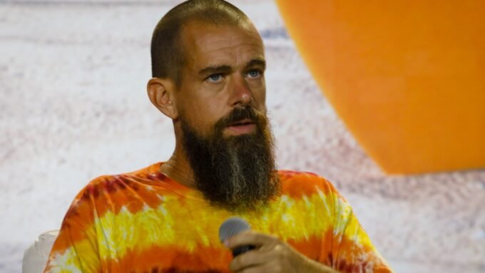 Block CEO Jack Dorsey speaking, with a stock chart showing a sharp increase in the background.