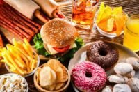 Un burger et des frites, symboles de la restauration rapide, posés sur une table, évoquant les risques pour la santé.