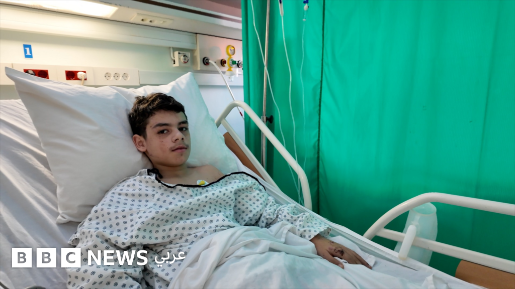 امرأة تنظر من نافذة مبنى متهالك في حي باب التبانة بطرابلس، لبنان، ترمز إلى أزمة السكن والإهمال.