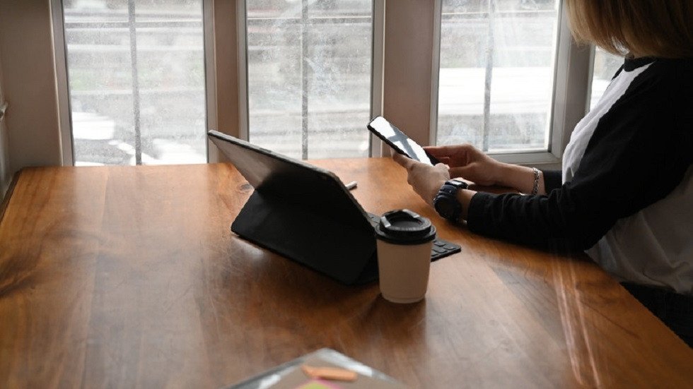 صورة تعبيرية لشخص يشعر بالتعب والإرهاق جراء الاستخدام المفرط للأجهزة الرقمية، مع خلفية تظهر أيقونات تطبيقات وشاشات.