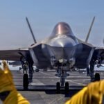 صورة تظهر أعلام الولايات المتحدة وإيران مع إشارة إلى التوترات الدبلوماسية والعسكرية المحتملة بين البلدين.