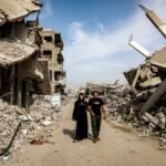 فلسطينية عائدة إلى غزة مع زوجها تسير بين ركام المباني المدمرة في مخيم جباليا.
