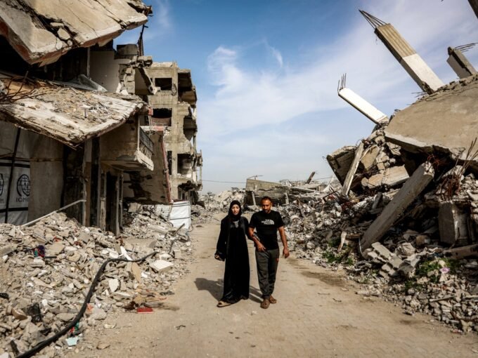 فلسطينية عائدة إلى غزة مع زوجها تسير بين ركام المباني المدمرة في مخيم جباليا.