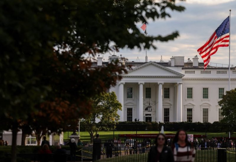 علم الولايات المتحدة يرفرف أمام البيت الأبيض بينما يمر الناس بجانبه، بعد أسابيع من استمرار إغلاق الحكومة الأمريكية، في واشنطن العاصمة، الولايات المتحدة، 24 أكتوبر 2025.