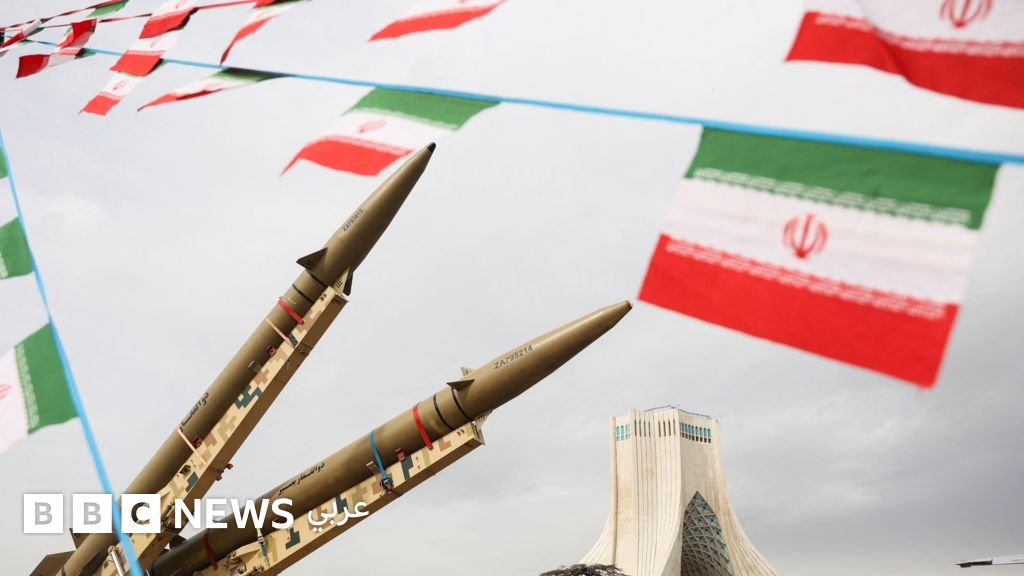 أعلام وصواريخ أمام برج آزادي في طهران خلال ذكرى الثورة الإسلامية، مع صورة أرشيفية لنتنياهو وترامب.