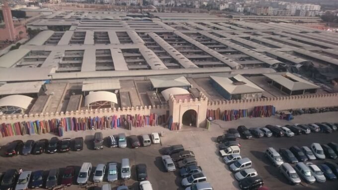 حافلات سياحية متوقفة أمام سوق الأحد بأكادير، تعكس تحديات مرآب السوق.