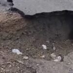 صورة تظهر تشققات واضحة على سطح الطريق الوطنية رقم 8 بإقليم الحسيمة، مع منازل سكنية أسفلها.