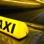 صورة لسيارة أجرة صفراء بجانب سيارة تابعة لتطبيق نقل ذكي في مدينة عمان، الأردن، ترمز إلى المنافسة بين القطاعين.