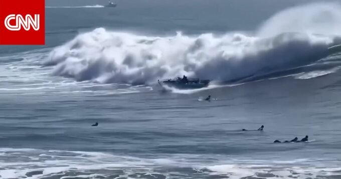 صورة لقارب مقلوب في البحر مع راكبي أمواج يهرعون لإنقاذ الركاب في سان خوسيه.