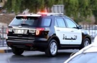 صورة لحقيبة ملقاة على جانب الطريق في منطقة حضرية، مع وجود عناصر أمنية في الخلفية