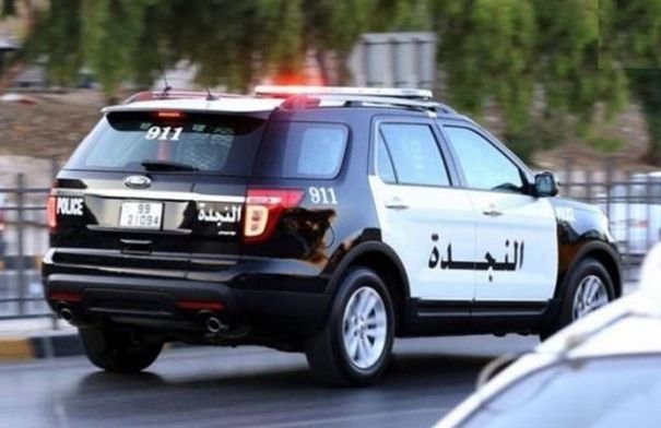 صورة لحقيبة ملقاة على جانب الطريق في منطقة حضرية، مع وجود عناصر أمنية في الخلفية