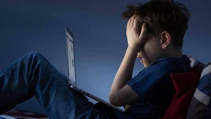 صورة تظهر طفلاً يستخدم جهازًا لوحيًا مع إشارة تحذير، ترمز لمخاطر الإنترنت على القاصرين.