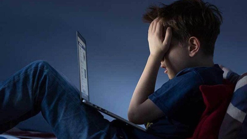 صورة تظهر طفلاً يستخدم جهازًا لوحيًا مع إشارة تحذير، ترمز لمخاطر الإنترنت على القاصرين.