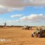 صورة جوية لقاعدة التنف العسكرية في البادية السورية، تظهر مركبات عسكرية ومباني، مع خلفية صحراوية واسعة.