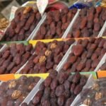 Assortiment de dattes marocaines et importées sur un étal de marché pendant le Ramadan, avec des sacs et des boîtes de différentes variétés.