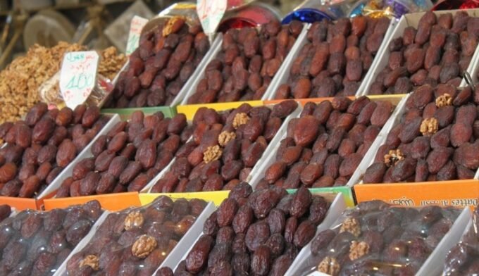 Assortiment de dattes marocaines et importées sur un étal de marché pendant le Ramadan, avec des sacs et des boîtes de différentes variétés.