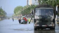 Vue aérienne d'une zone inondée au Maroc, avec des maisons partiellement submergées et des champs sous l'eau, symbolisant les crues et l'attente de la décrue.