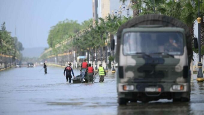 Vue aérienne d'une zone inondée au Maroc, avec des maisons partiellement submergées et des champs sous l'eau, symbolisant les crues et l'attente de la décrue.