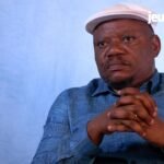 RDC : Jean-Marc Kabund, l'opposant qui défie Tshisekedi sur le dialogue national 4 Jean-Marc Kabund s'exprimant lors d'une interview, avec un arrière-plan neutre, symbolisant son rôle d'opposant politique en RDC.