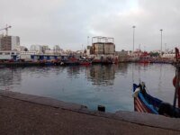 Vue aérienne du port de pêche de Casablanca, montrant des bateaux amarrés et les infrastructures portuaires sous un ciel clair.
