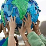 Une main tenant un globe terrestre miniature, symbolisant la protection de l'environnement et l'économie circulaire.