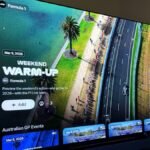 A sleek Apple TV interface displaying the Formula 1 logo and race schedule, with a blurred F1 car on a track in the background.