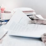 A person reviewing a thick franchise agreement document with a magnifying glass, symbolizing strategic analysis.