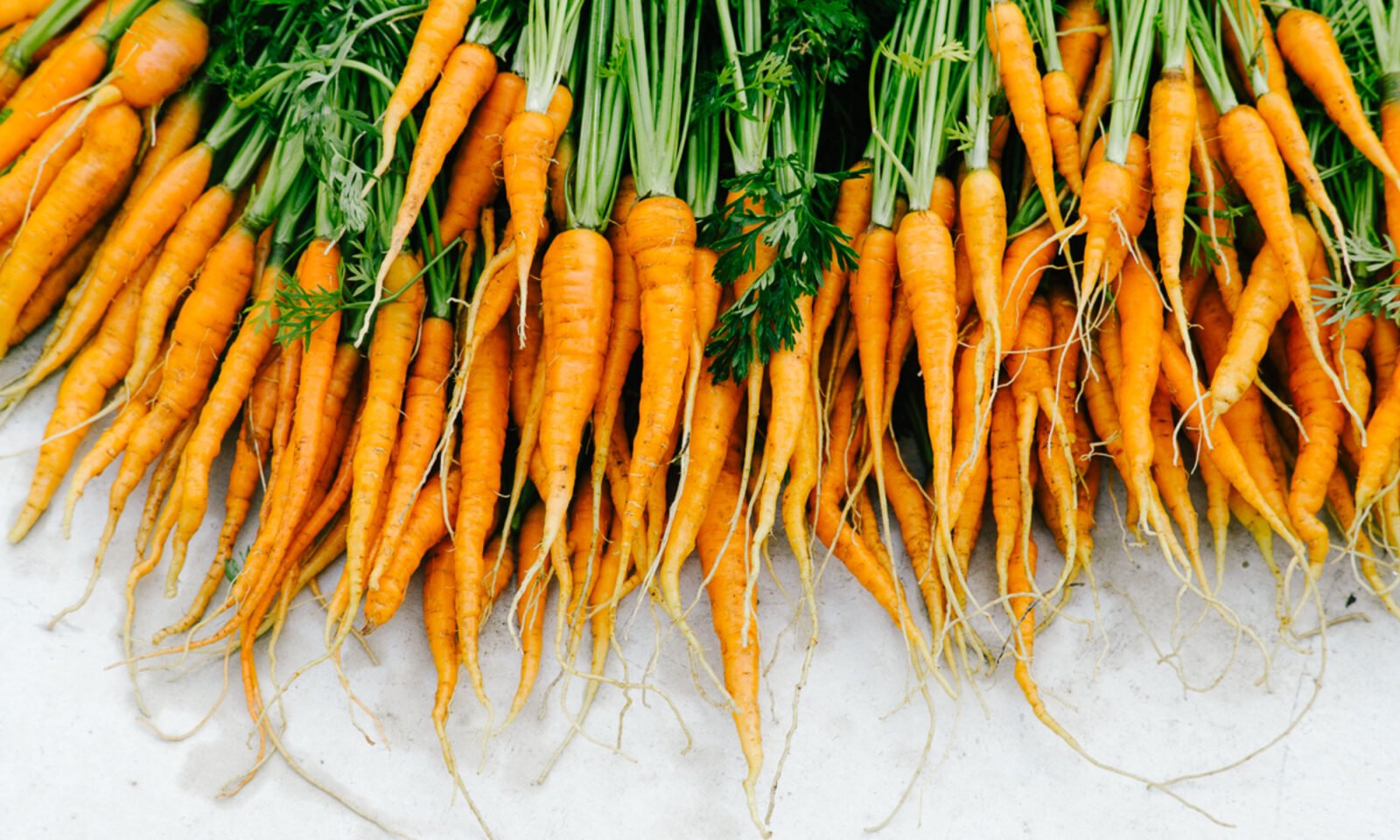 Fresh vegetables like celery, asparagus, and carrots stored upright in glass jars with water in a refrigerator