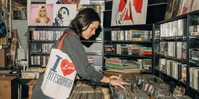 A young person holding a vinyl record, surrounded by books and a record player.