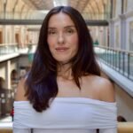 A young Gen Z woman, looking determined, with abstract tech and startup elements in the background, symbolizing her journey from entrepreneurship to corporate and back.