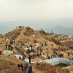 Vue aérienne de la mine de coltan de Rubaya en RDC, un site d'extraction à ciel ouvert avec des collines et des zones d'excavation.