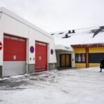 Vue panoramique de l'hôpital de Nuuk, Groenland, avec des montagnes enneigées en arrière-plan et un ciel clair, symbolisant l'autonomie et la résilience de l'île face aux pressions extérieures.
