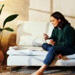 A journalist smiling, holding a glass of a watermelon-flavored drink, representing improved gut health and wellness.