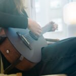 The Openhagen Harmoni Guitar with its magnetic stand and Nordic horse capo, showcasing its elegant mahogany finish.