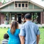 A diverse group of people looking at a new house, symbolizing hope for affordable homeownership.