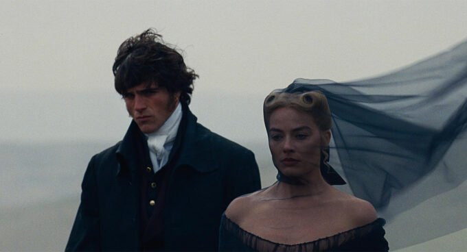 Margot Robbie et Jacob Elordi dans une scène intense du film Hurlevent, sur fond de paysages tourmentés.