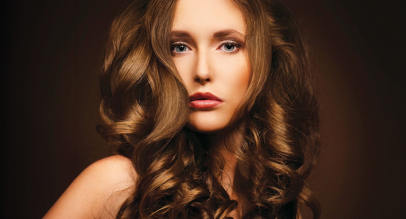 Gros plan sur une chevelure saine et brillante, symbolisant l'équilibre parfait entre hydratation et nutrition pour des cheveux sublimés.