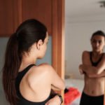 A person spraying hypochlorous acid mist on their face after a workout at the gym