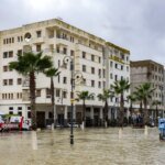 Vue aérienne d'une zone résidentielle marocaine inondée, avec des maisons partiellement submergées et des routes impraticables, symbolisant les dégâts des inondations.