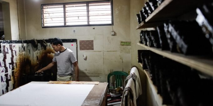 Indonesian textile factory with traditional batik fabric patterns in the foreground