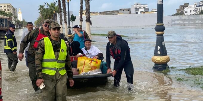 Vue aérienne de Ksar El Kébir sous la pluie, avec des routes inondées et des véhicules d'évacuation.