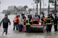 Vue aérienne d'une zone inondée au Maroc, avec des habitations entourées d'eau et des équipes de secours en action.