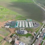 Vue aérienne du barrage Oued El Makhazine en situation de saturation, avec les eaux débordant presque, sous un ciel menaçant.