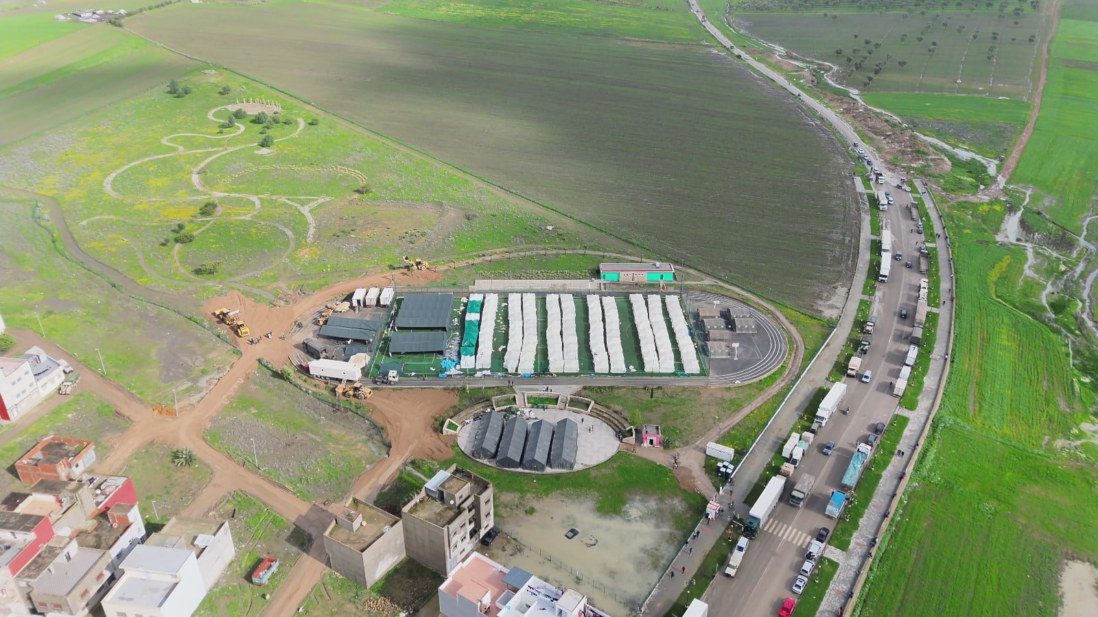 Vue aérienne du barrage Oued El Makhazine en situation de saturation, avec les eaux débordant presque, sous un ciel menaçant.
