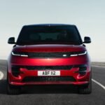 Un SUV Land Rover Defender Dakar D7X-R en pleine action dans le désert, avec un Range Rover Sport et une Jaguar F-PACE en arrière-plan, symbolisant la performance et l'innovation des marques en 2025 et 2026.