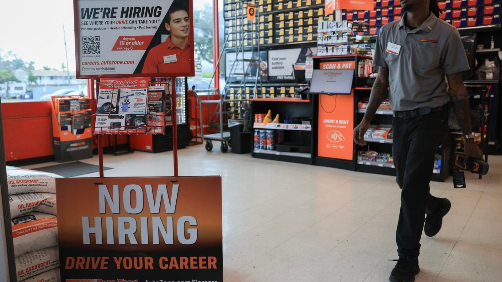 A 'Now Hiring' sign displayed at an AutoZone store, symbolizing current labor market conditions.